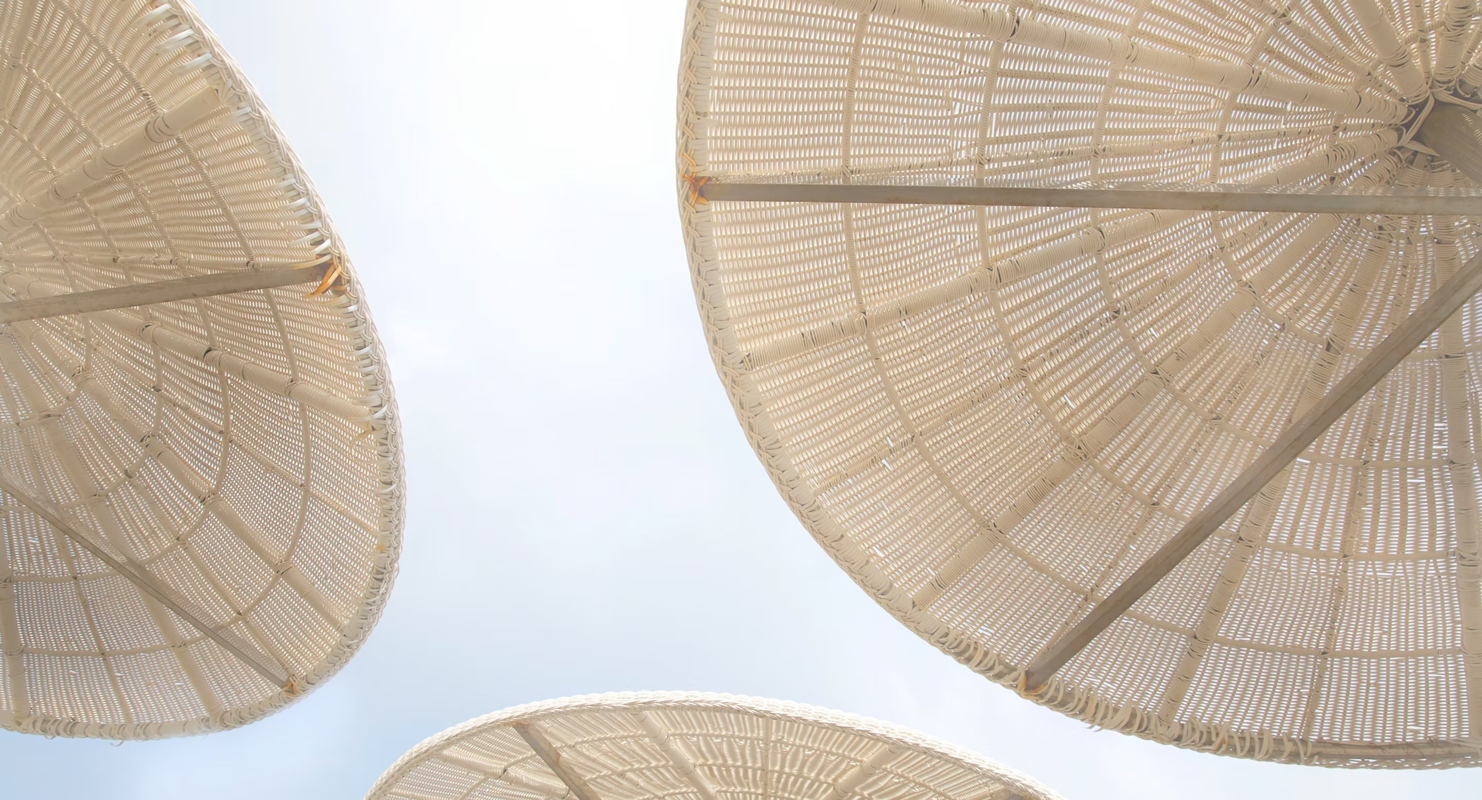 Woven umbrellas against the sky