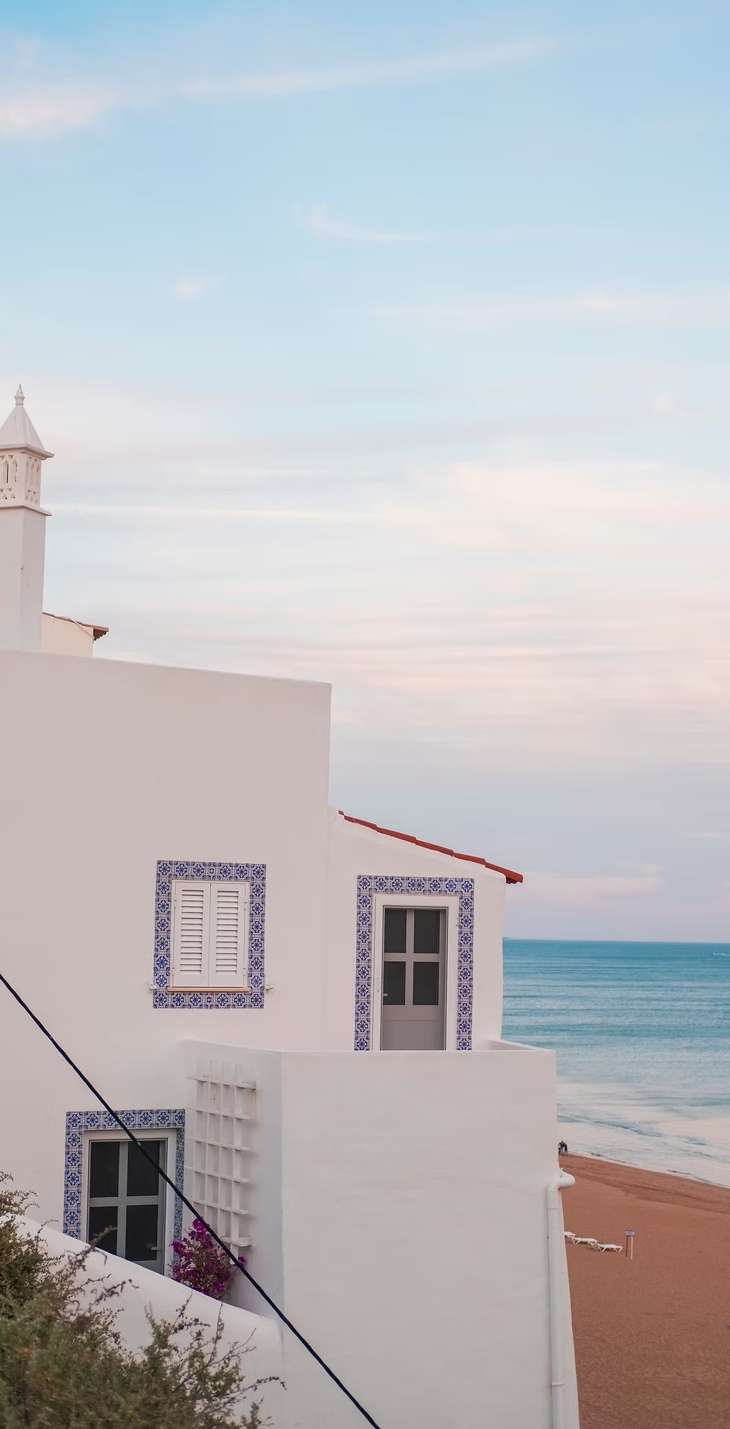 Whitewashed building with blue azulejo tiles overlooking the sea